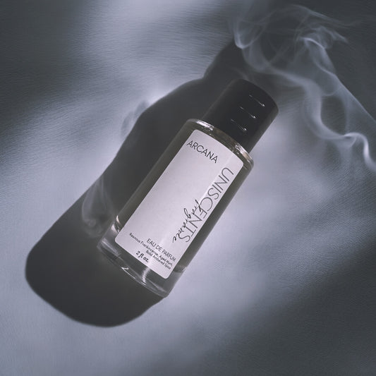 A bottle of perfume with a simple design, placed on a marble surface, surrounded by a few wisps of smoke.