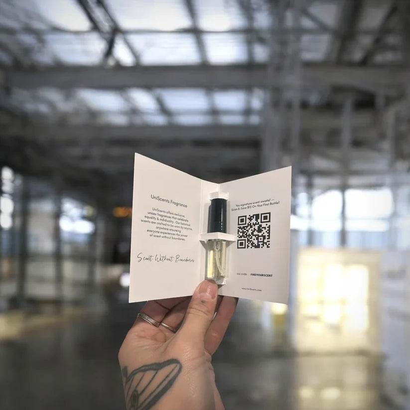 Hand holding a small bottle with a dropper and an open card with text and a QR code, against a blurred indoor background.