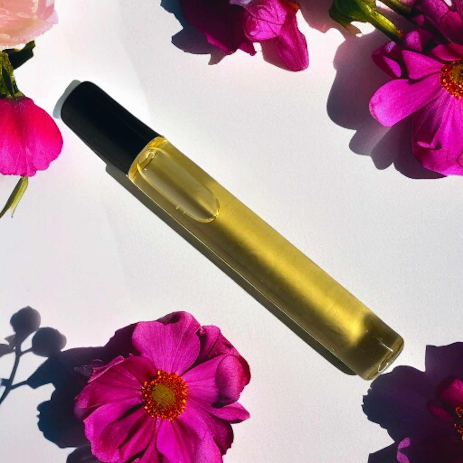 Yellow glass bottle with black cap on pink flowers background